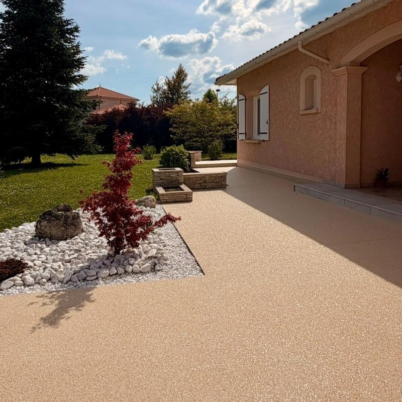 Terrasse ensoleillée à l'arrière d'une maison en bois de pêcher, avec aménagement paysager en gravier, un arbuste rouge et des marches en pierre.