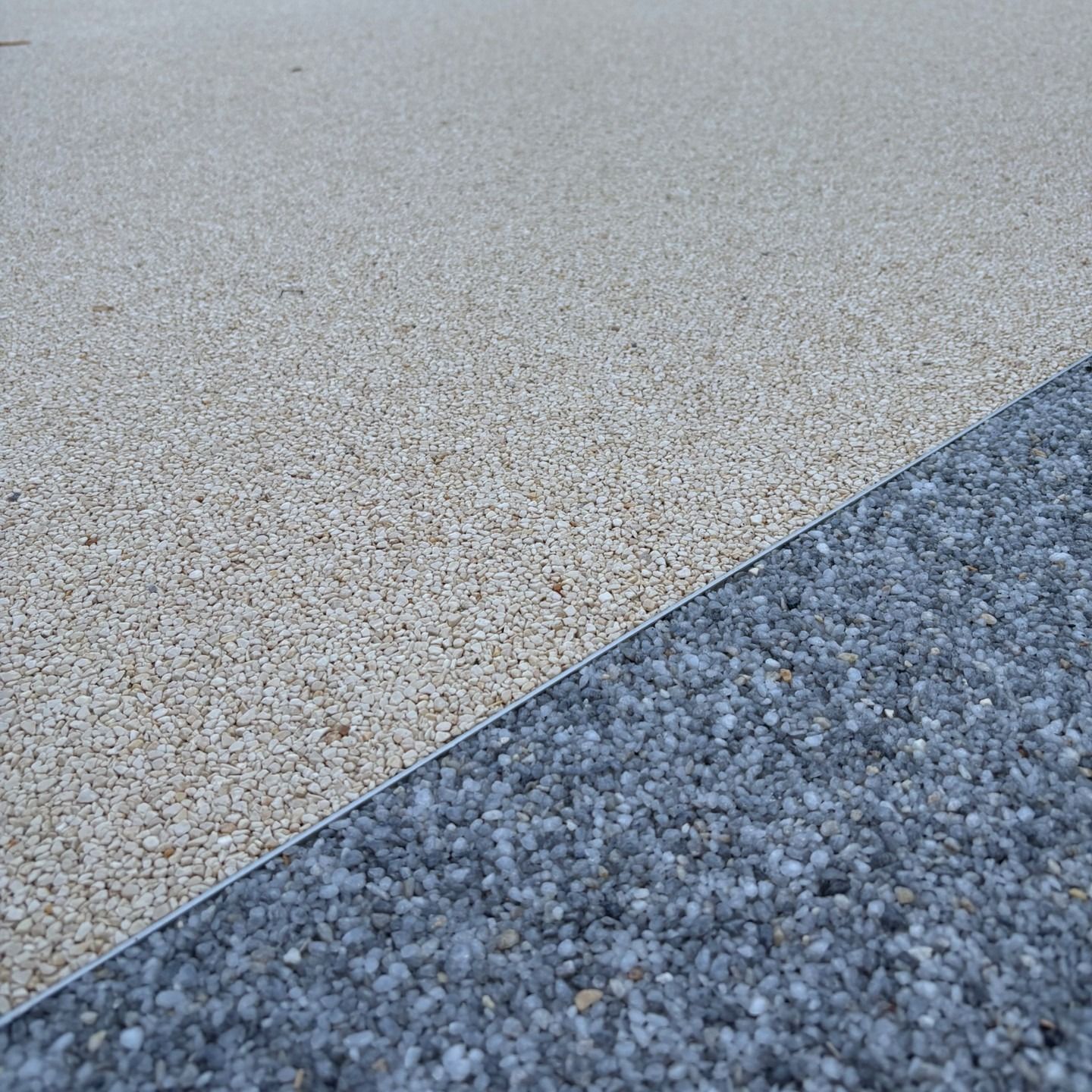 Deux surfaces de pavage texturées se rejoignant au niveau d'une couture diagonale, l'une beige clair et l'autre bleu-gris foncé.