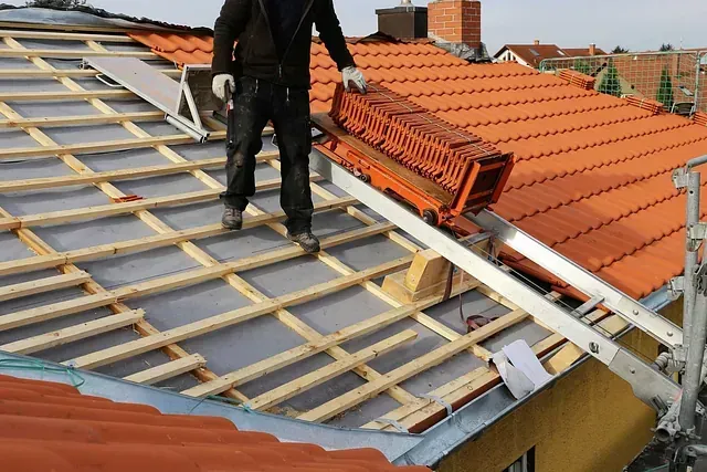Techador sobre un tejado inclinado, transportando una sección de andamio de color rojo anaranjado durante la renovación.