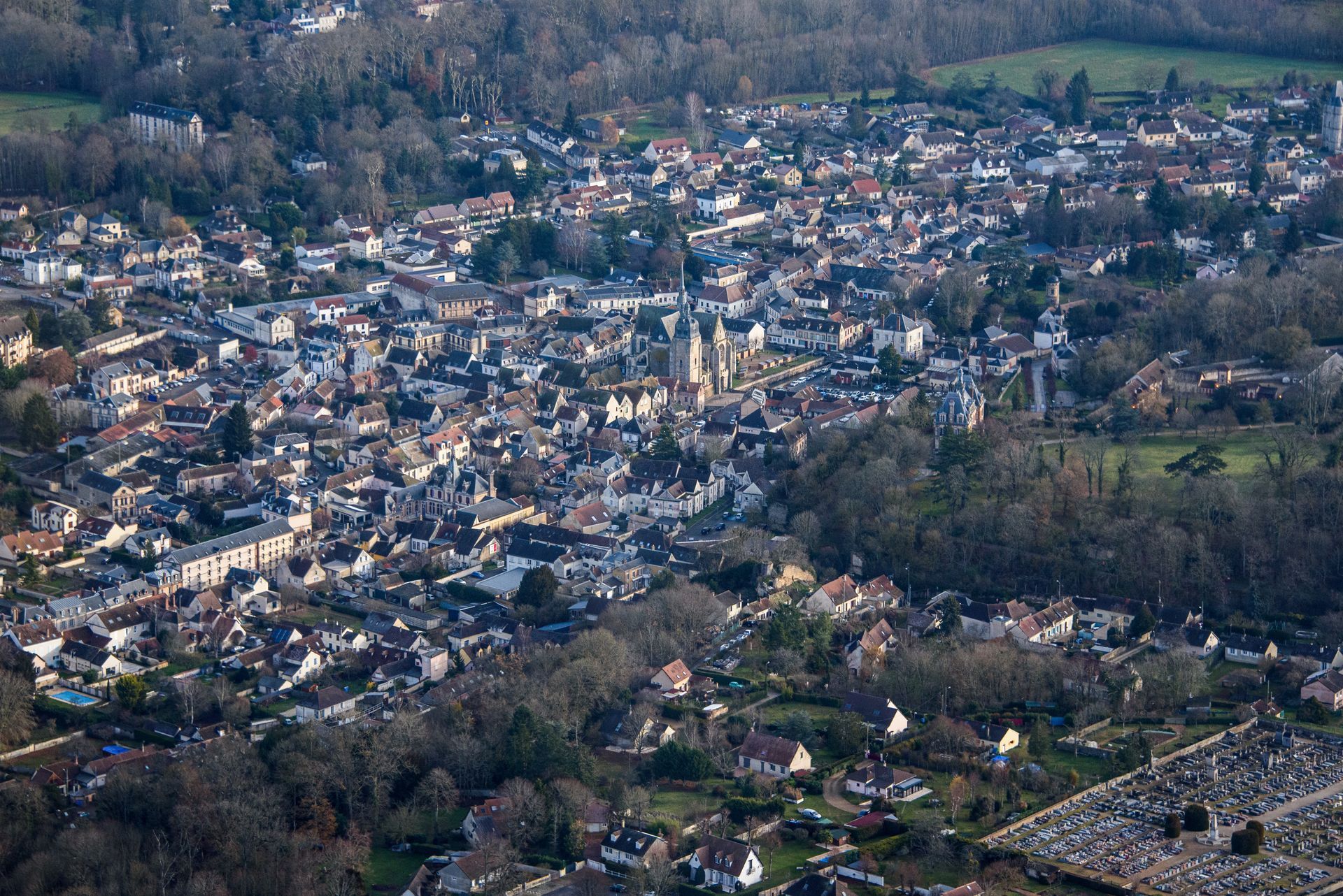 Vue aérienne de la ville de Nogent-le-Roi avec de nombreux bâtiments entourés d'arbres et d'un cimetière.