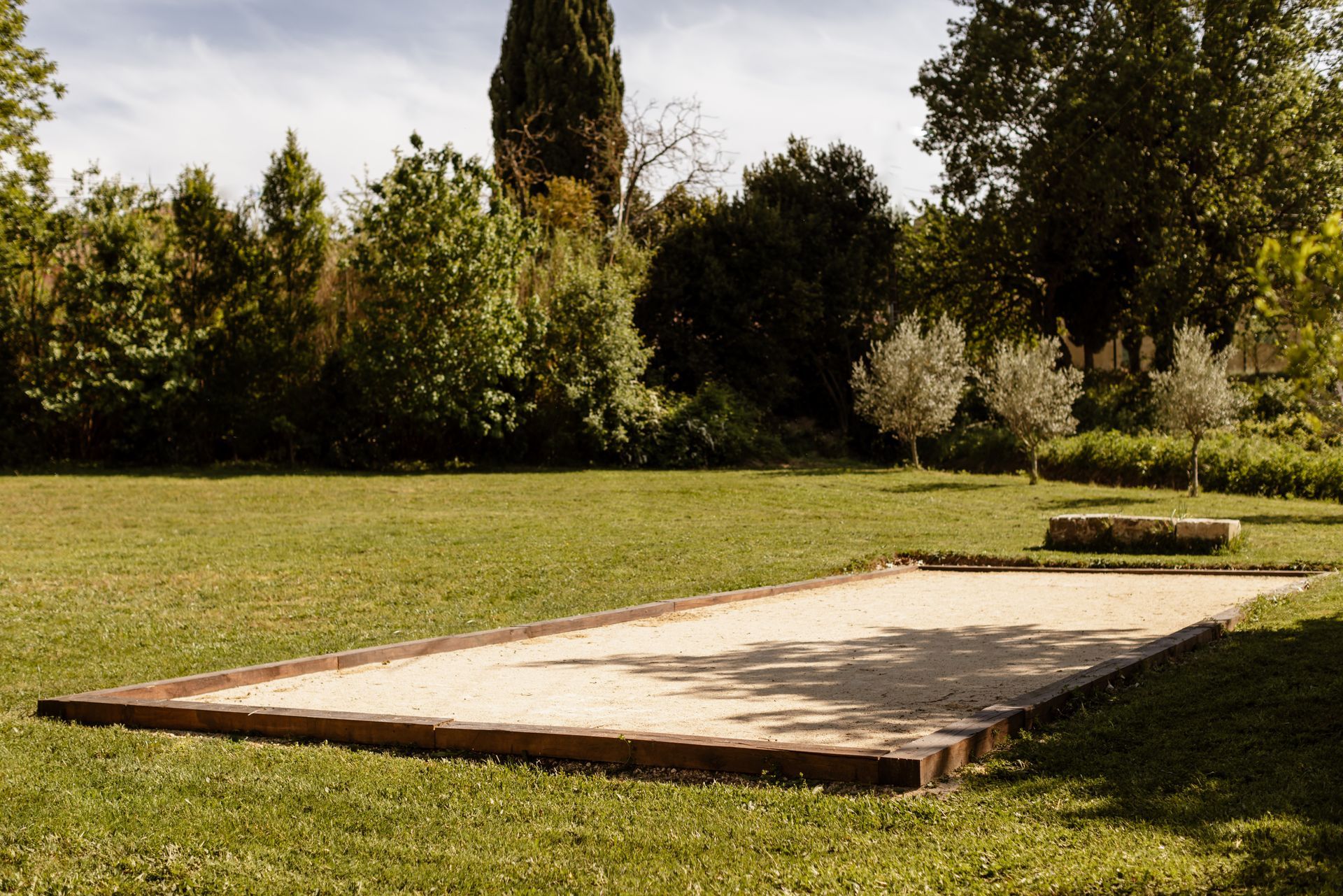 Terrain de pétanque sur gazon avec des arbres en arrière-plan.