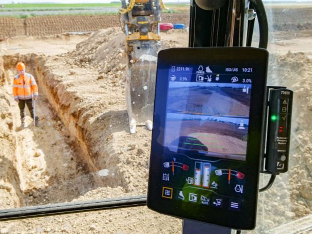 Un chantier de construction avec un écran vidéo de précision montrant des travaux d'excavation.