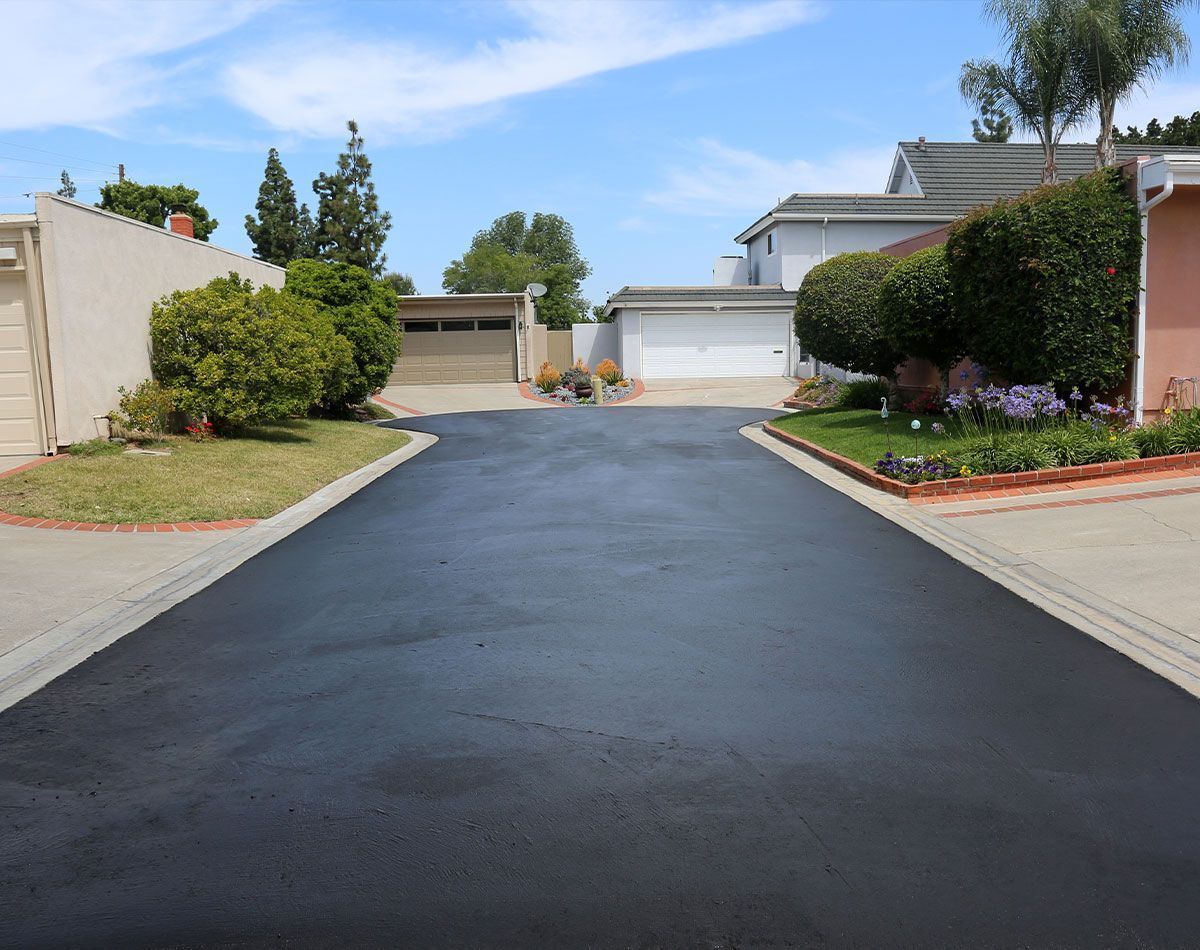 Allée asphaltée fraîchement pavée menant aux maisons par une journée ensoleillée.