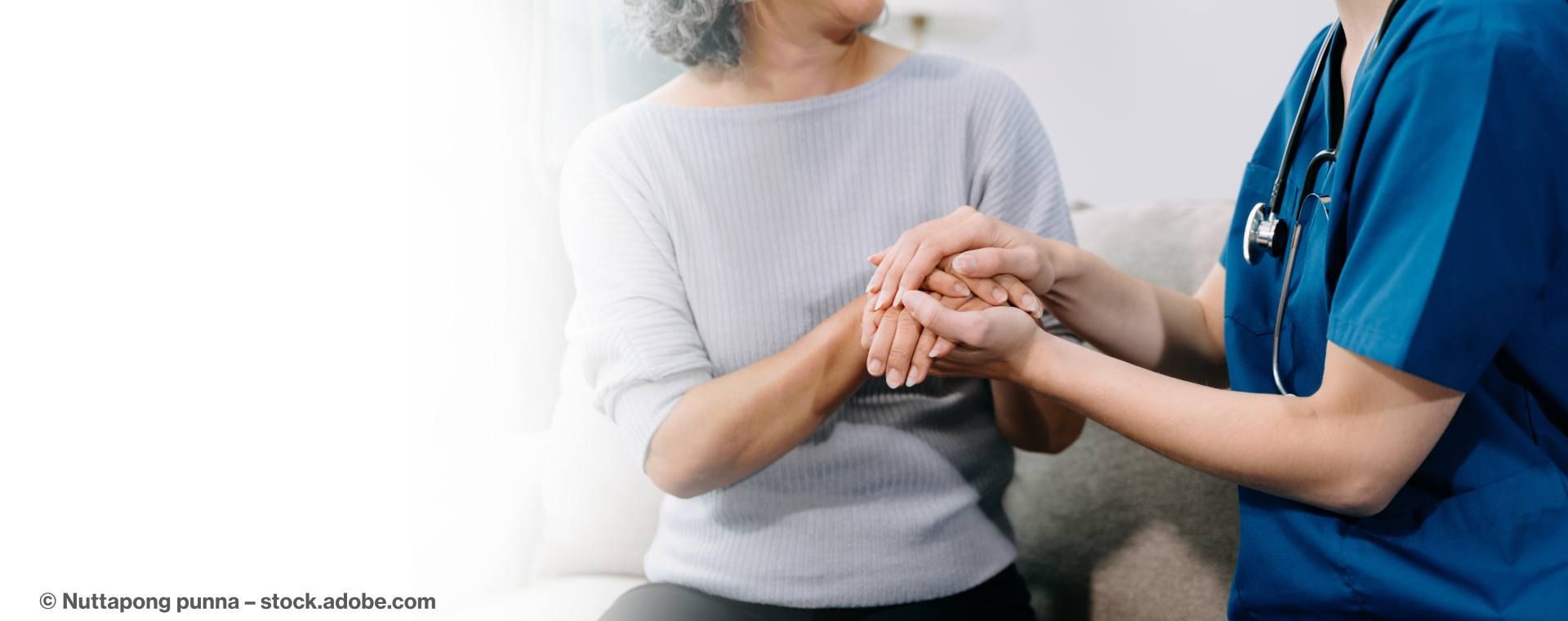 Pflegerin hält die Hand einer Seniorin
