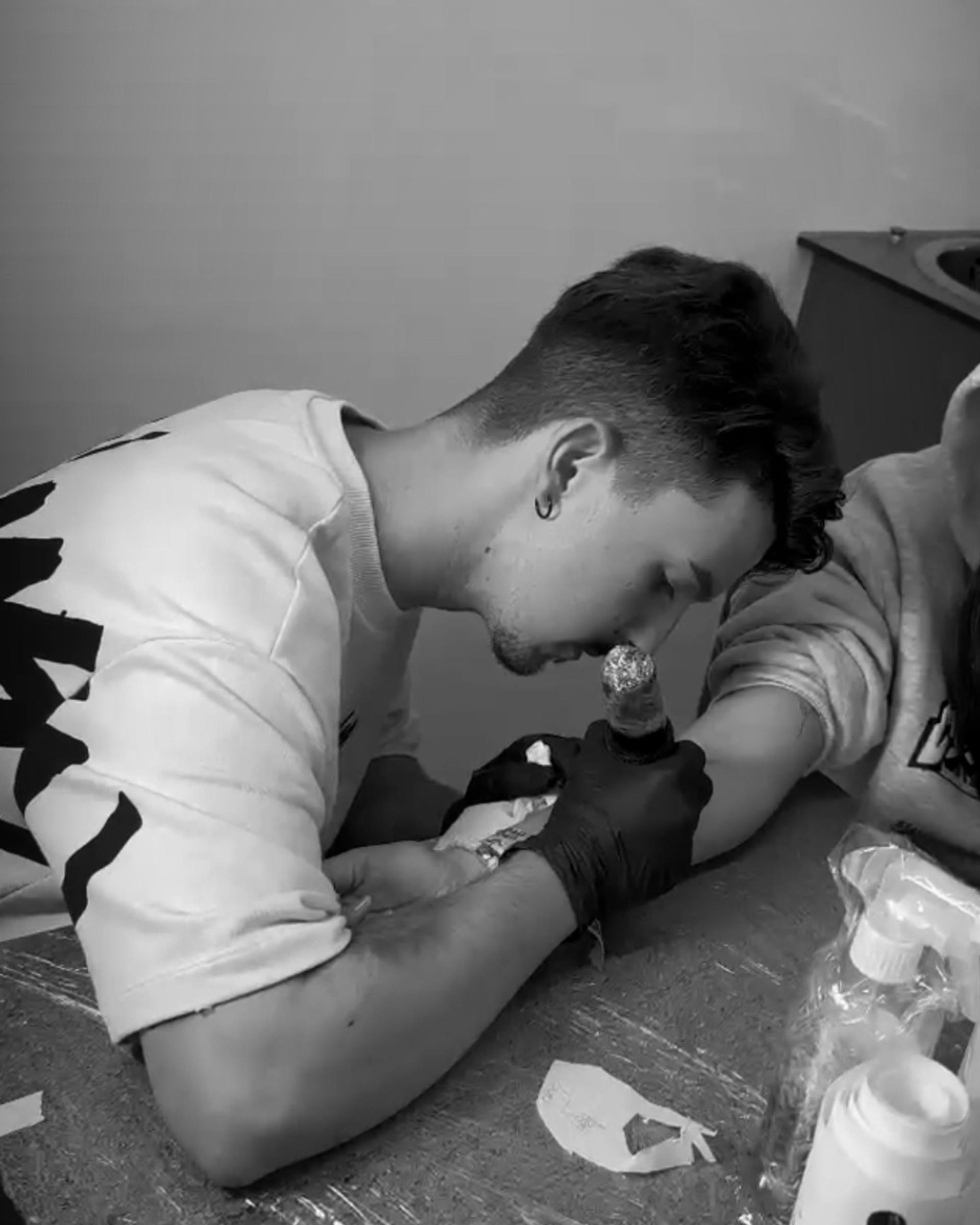 Un hombre se hace un tatuaje en el brazo de otro hombre.