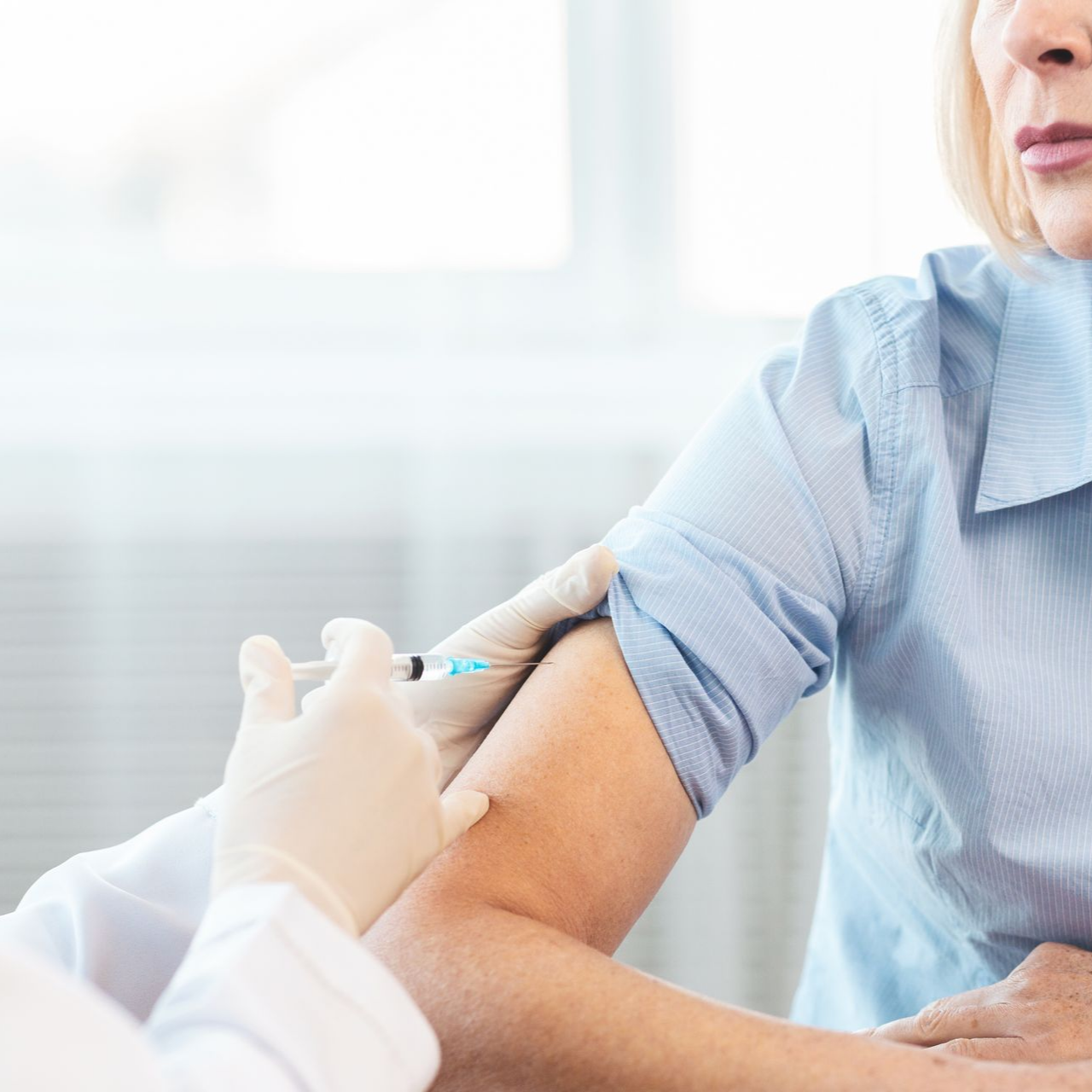 Un professionnel de santé administre une injection dans le bras d'un patient dans une salle de clinique lumineuse