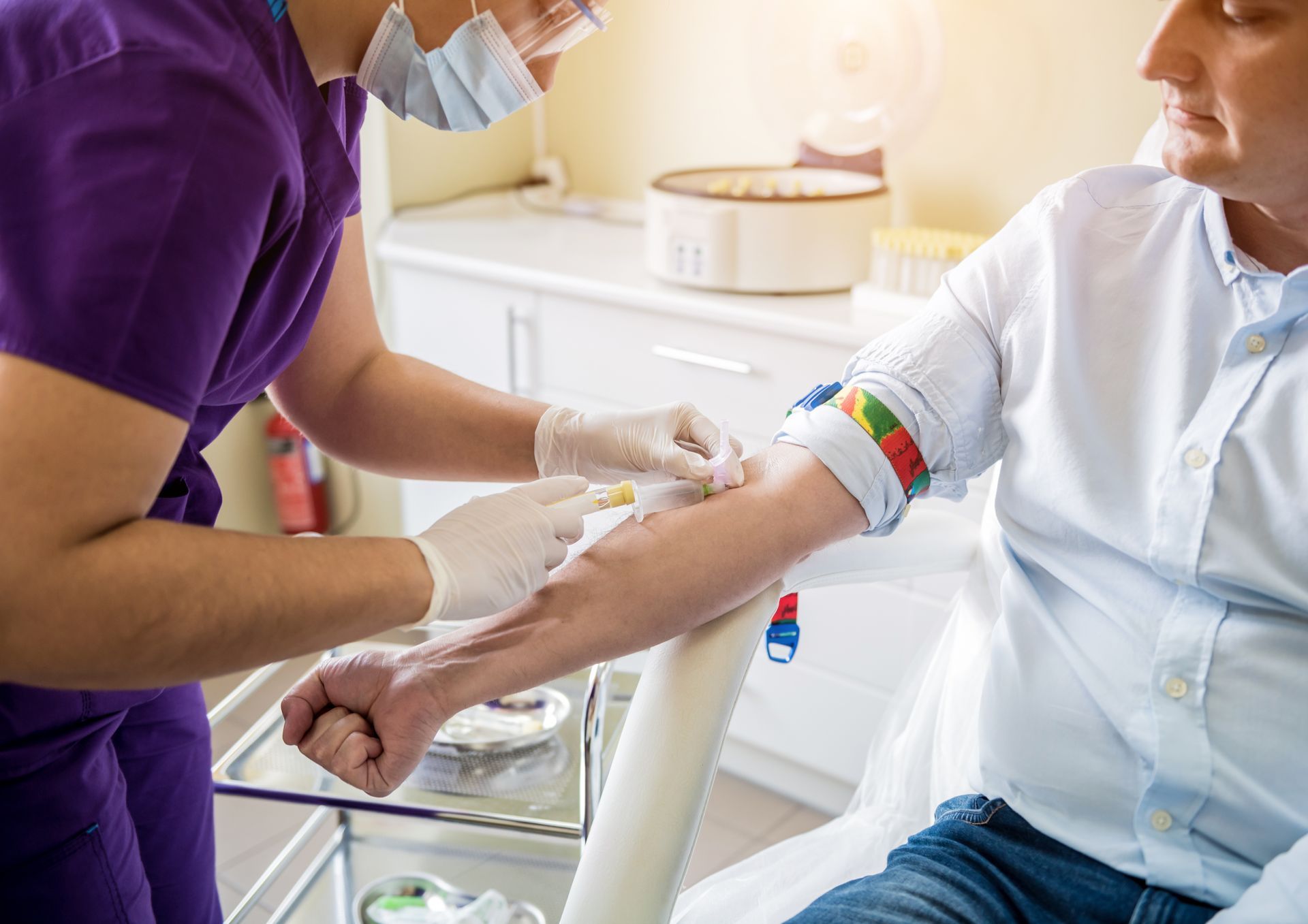Une infirmière prélève du sang sur un patient assis dans une clinique.