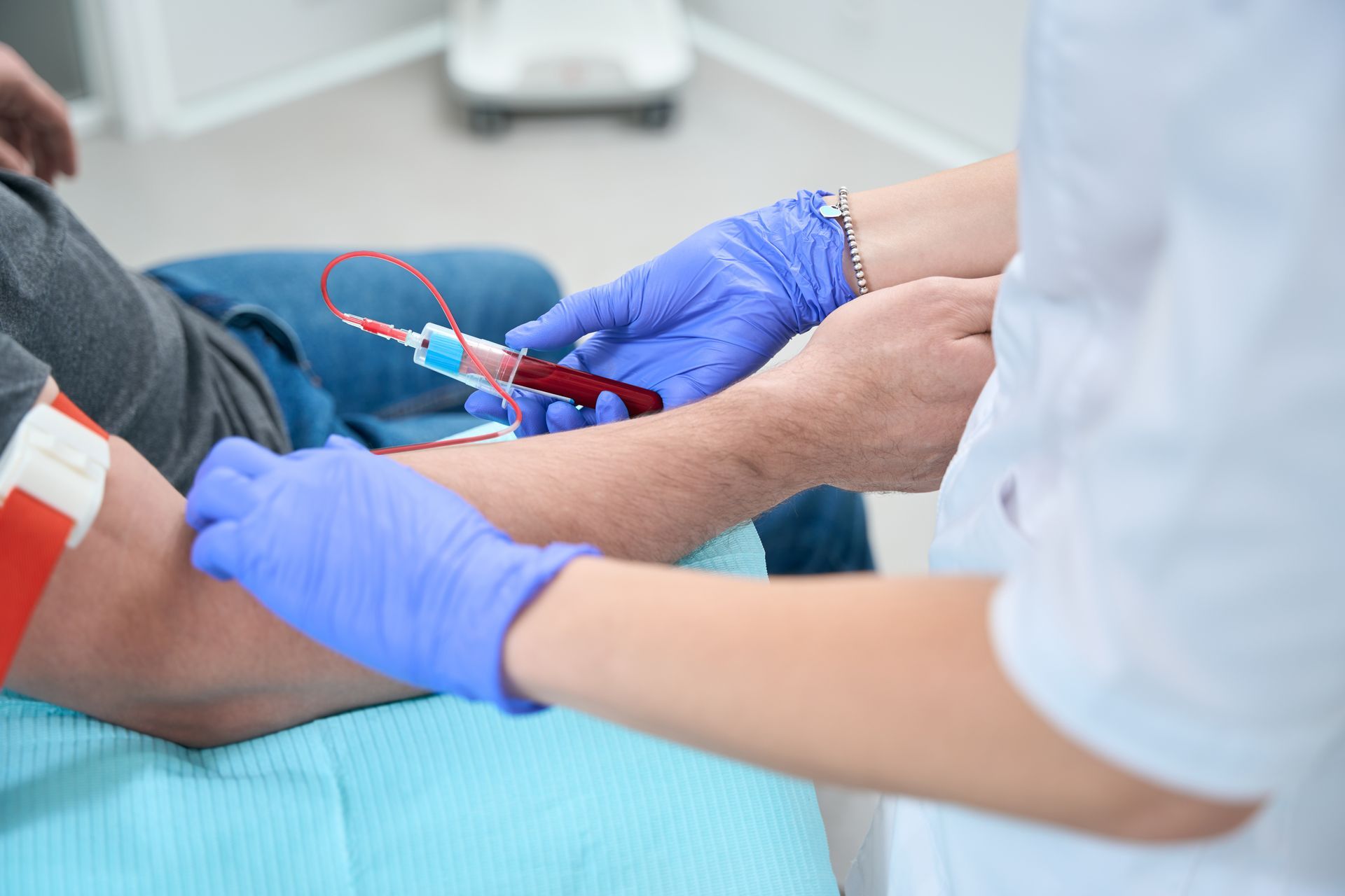 Un professionnel de santé ganté prélève un échantillon de sang au bras d'un patient à l'aide d'une seringue.