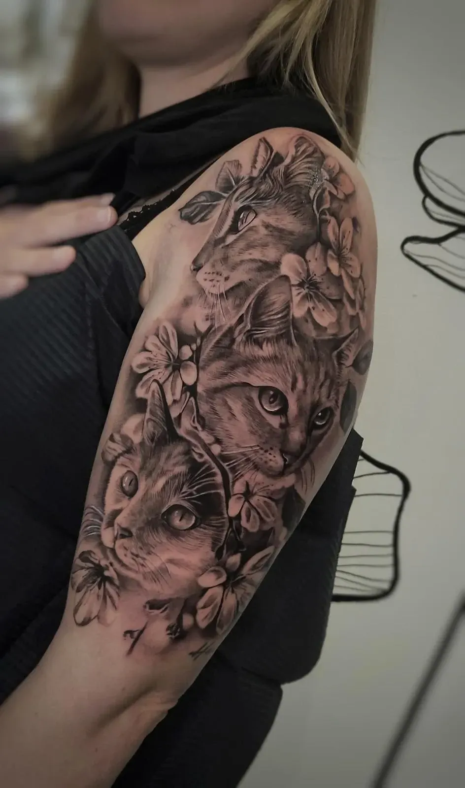 Primer plano de un brazo con un gran tatuaje de un lobo en negro y gris rodeado de flores.