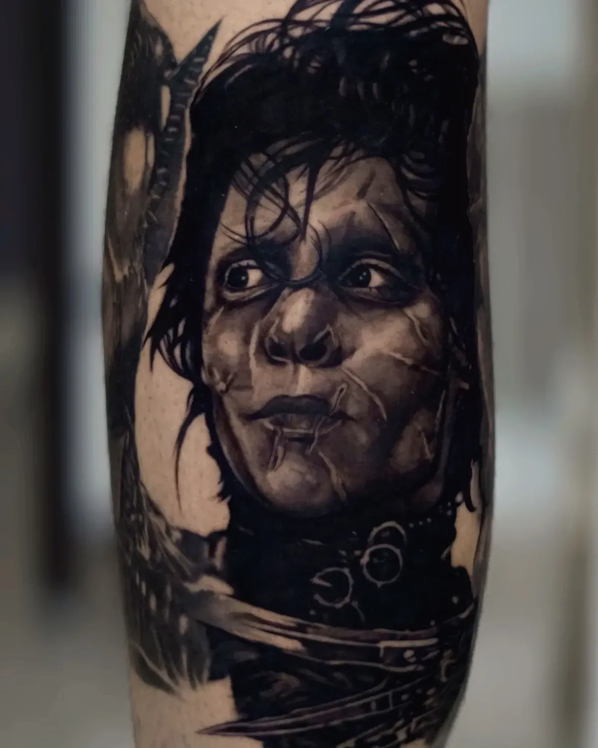 Retrato de tatuaje en blanco y negro de una figura con los ojos muy abiertos, cicatrices, el cabello oscuro