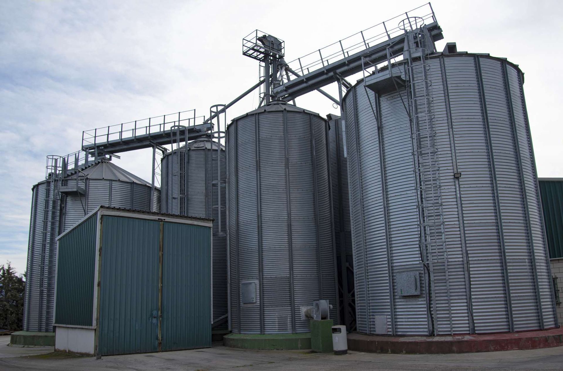 Una fila de silos con un edificio verde al fondo