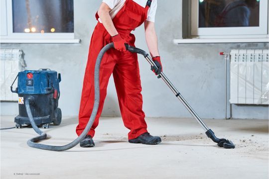Person reinigt den Boden mit einem Industriestaubsauger