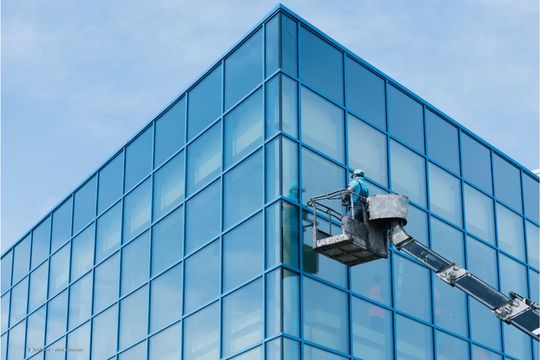 Fensterreiniger an einer Gebäudeecke mit einem Krank