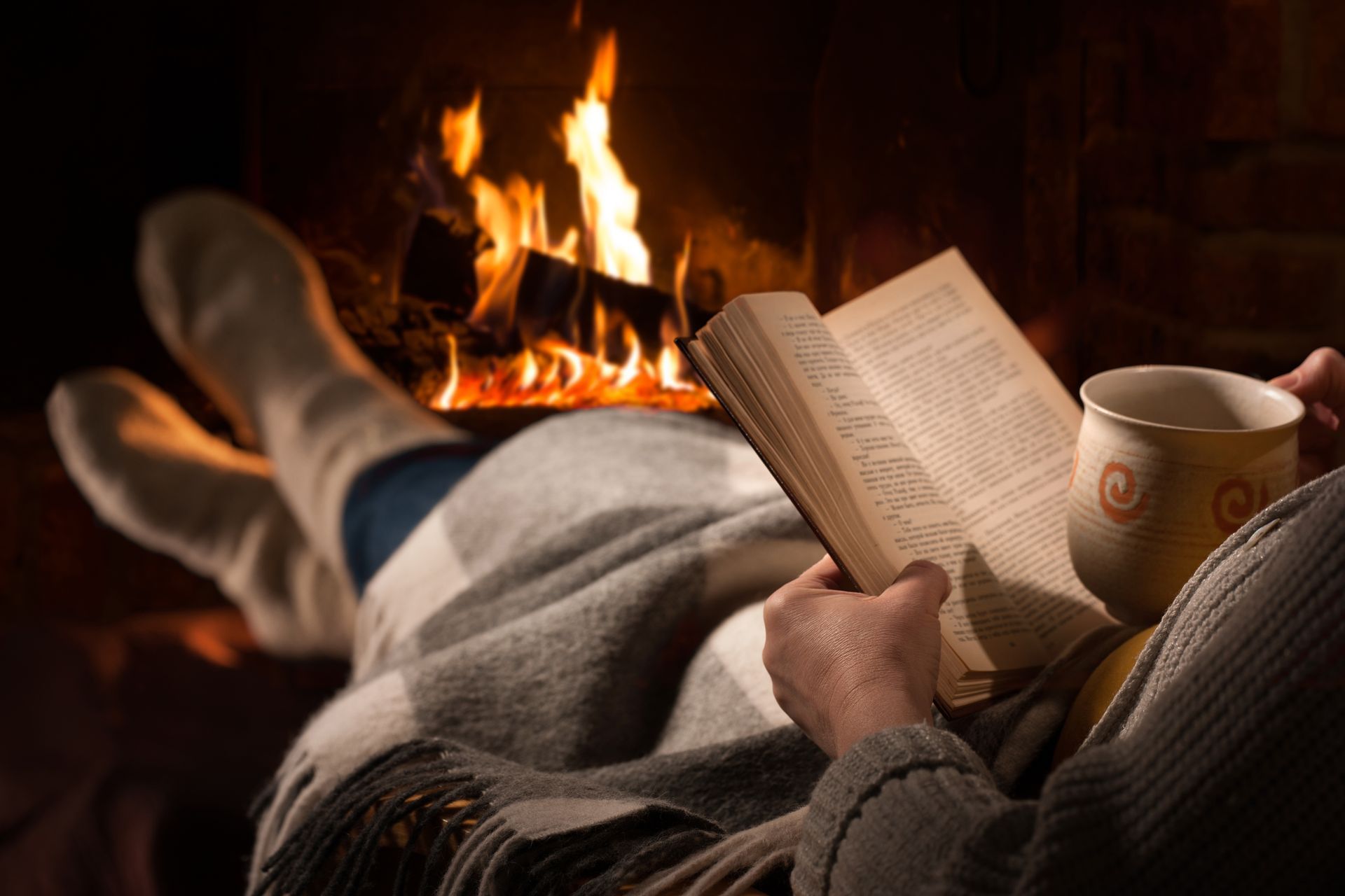 Une personne qui lit un livre devant une cheminée