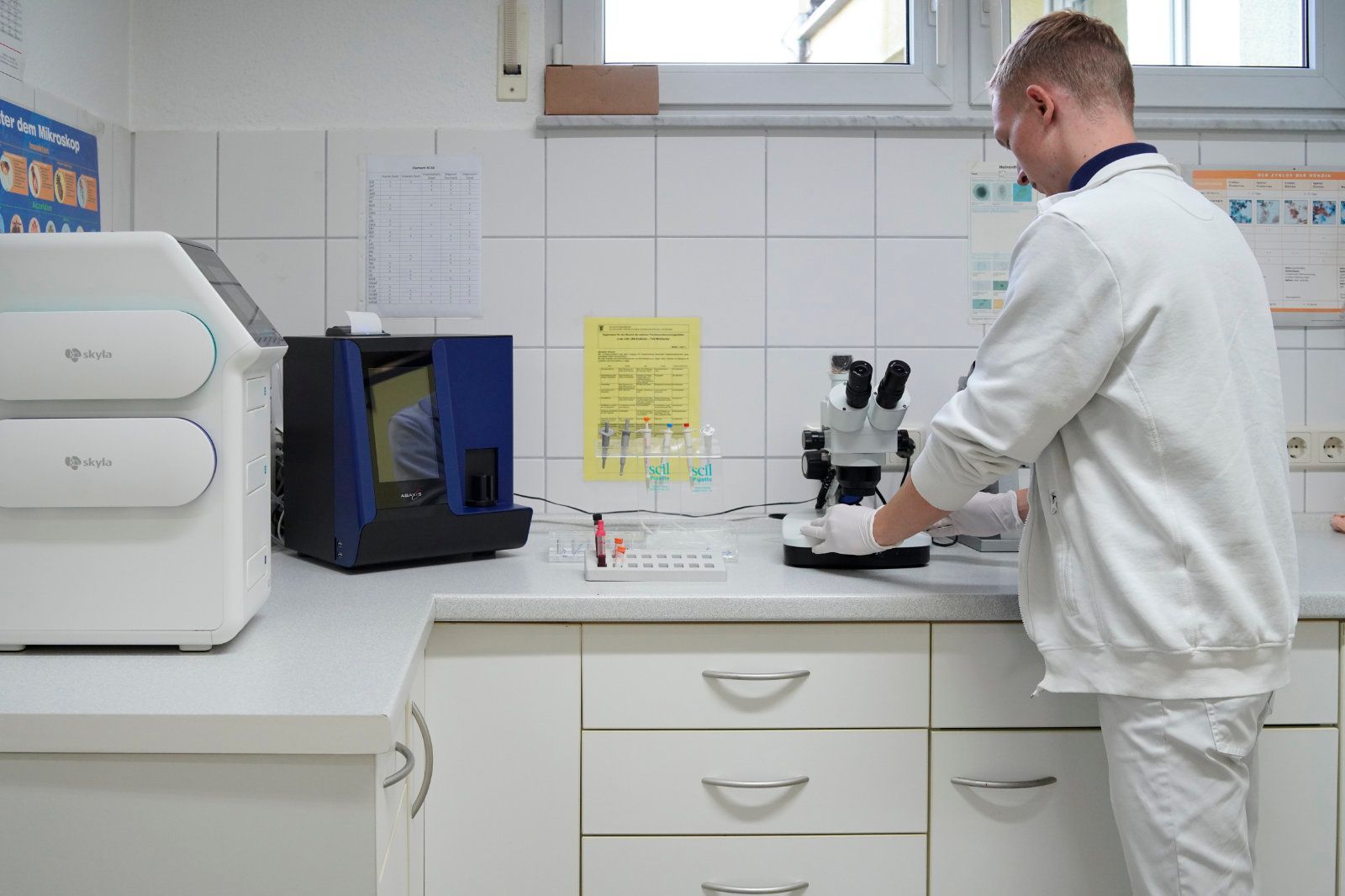 Ein Mann schaut in einem Labor durch ein Mikroskop.