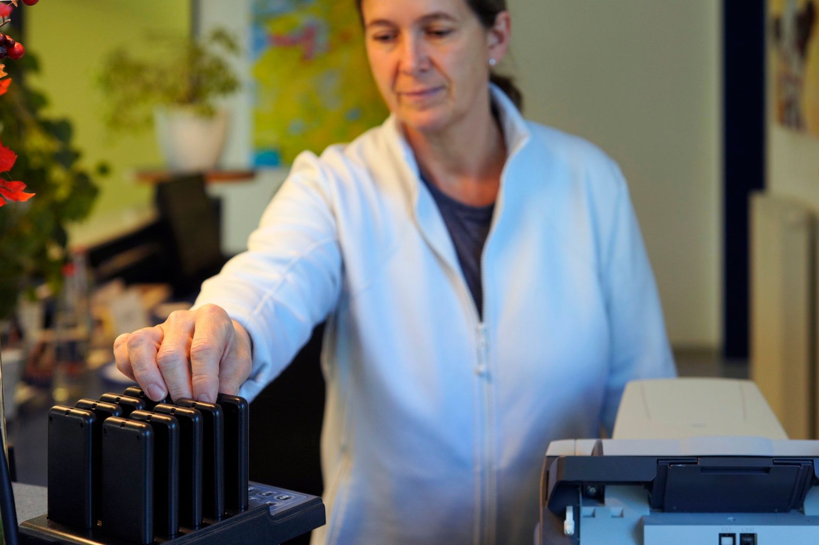 Eine Frau in einer weißen Jacke steht vor einem Drucker.