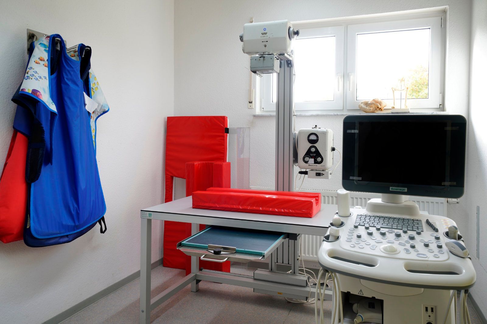 Ein Raum mit Tisch, Monitor und Röntgengerät.