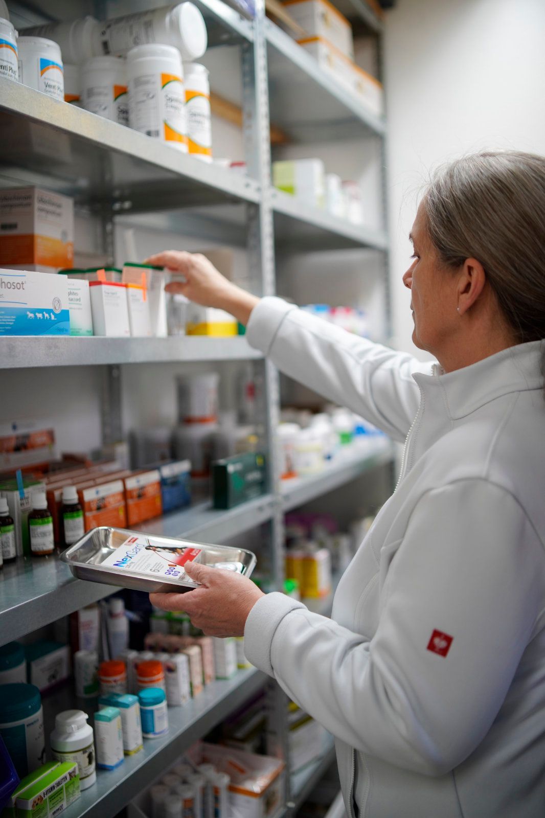 Eine Frau betrachtet in einer Apotheke ein Tablett mit Pillen.