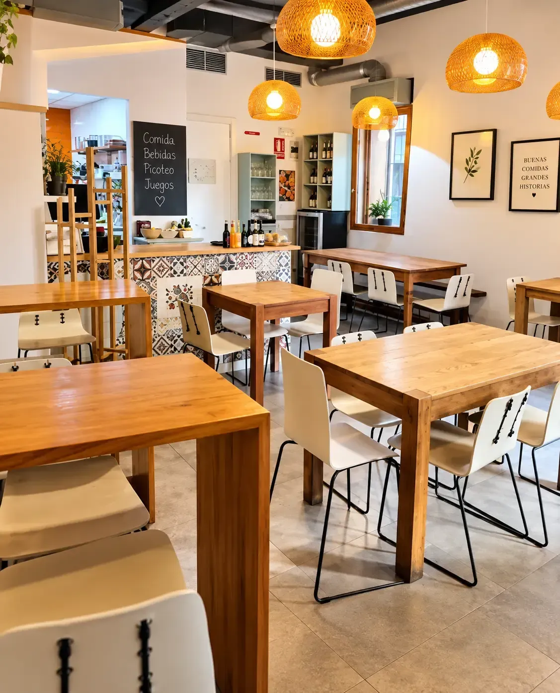 Interior acogedor de cafetería con mesas de madera, sillas blancas y cálidas lámparas colgantes.
