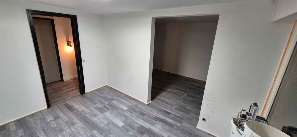 Ein leerer Raum mit Holzboden und weißen Wänden.