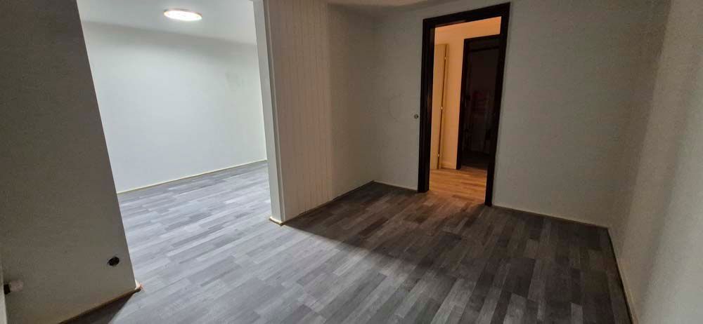 Ein leerer Raum mit Hartholzböden und einer Tür, die zu einem Flur führt.