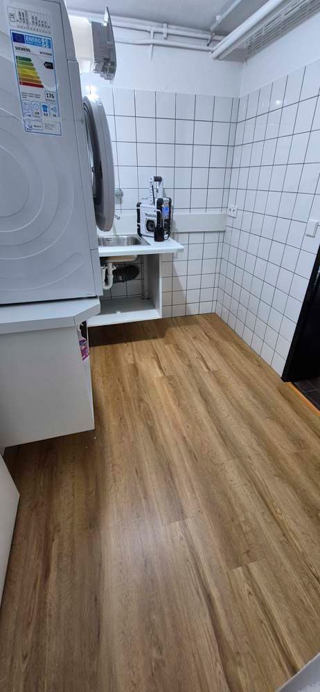 Eine Küche mit Holzboden, Kühlschrank und Spüle.