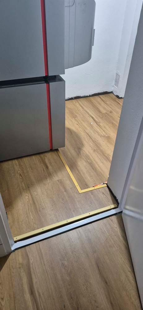 Eine Nahaufnahme eines Holzbodens neben einer Tür.