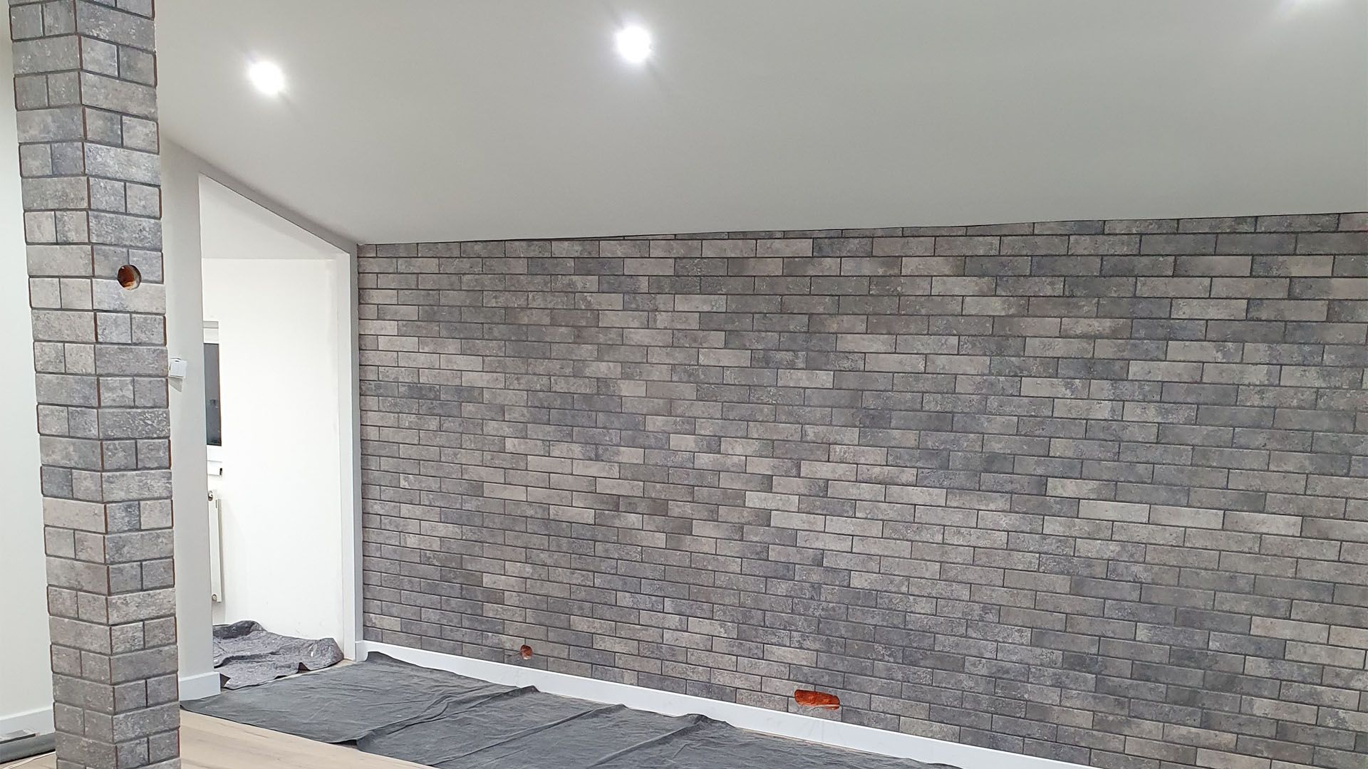 ein Raum mit einer Backsteinwand und einer weißen Decke.