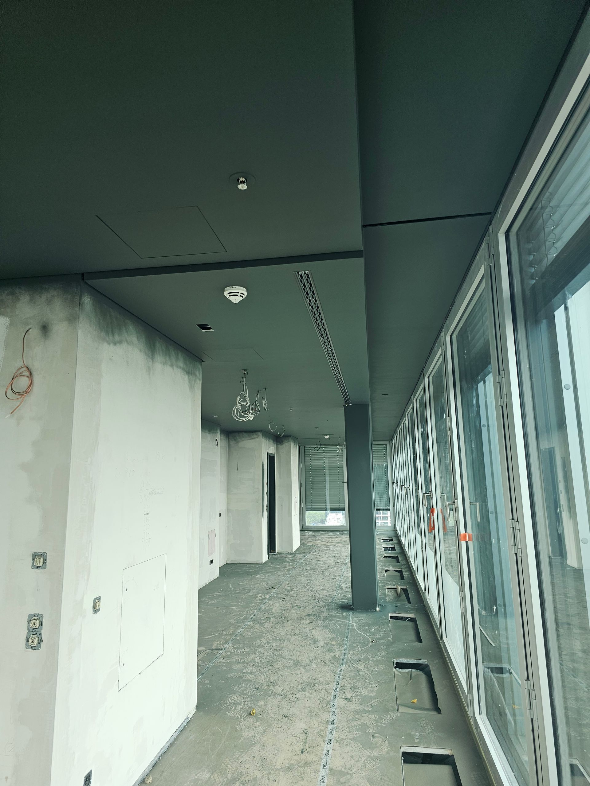 Ein langer Flur mit vielen Fenstern in einem im Bau befindlichen Gebäude.