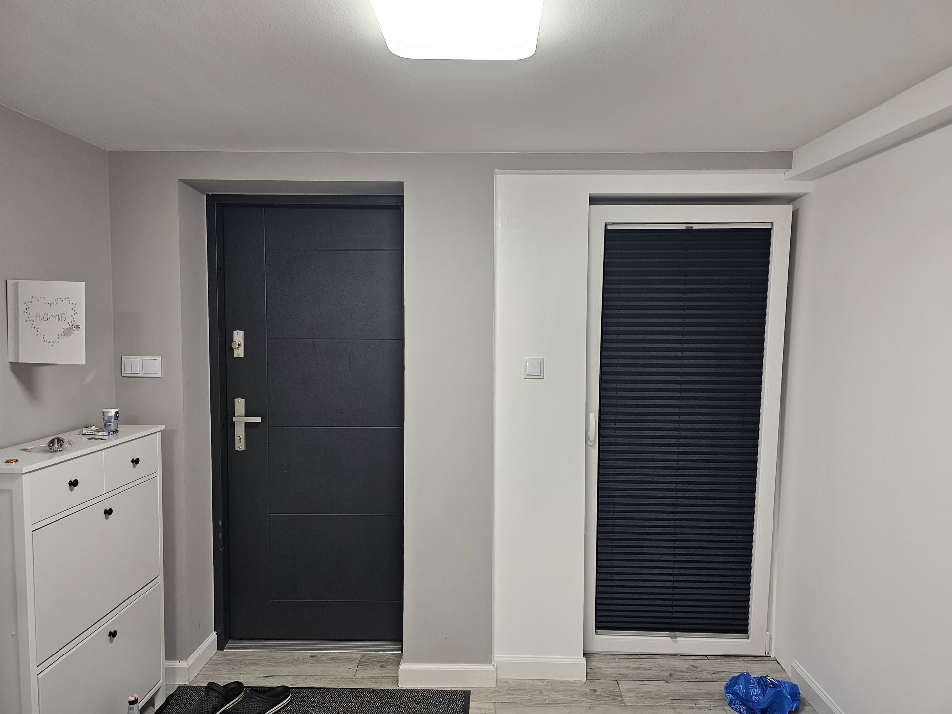 ein Flur mit einer schwarzen Tür und einer weißen Kommode.