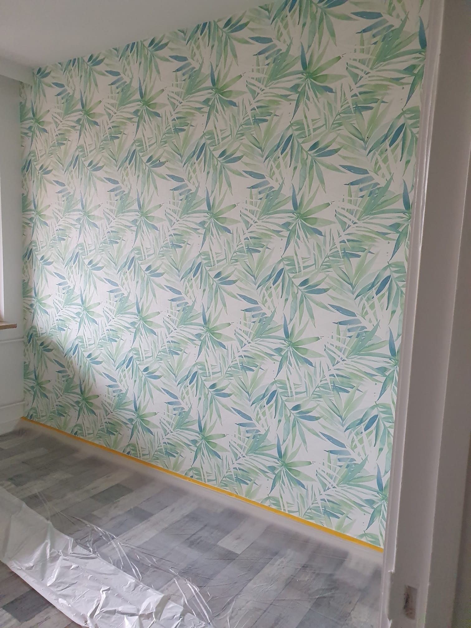 ein Zimmer mit einer grün-weißen Tapete an der Wand.