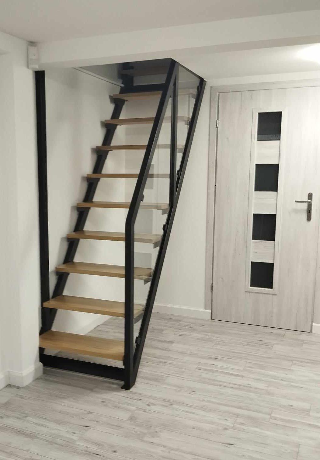 eine Holztreppe in einem Raum neben einer Tür.