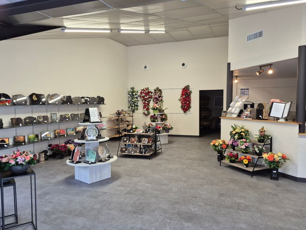 Vue intérieure d'une salle d'exposition de pompes funèbres présentant des urnes, des compositions florales