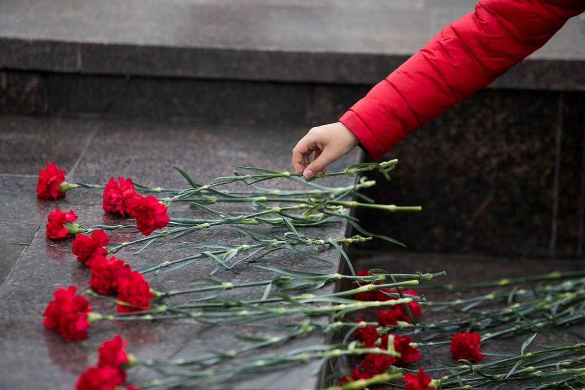 Femme qui pose des roses sur une tombe.