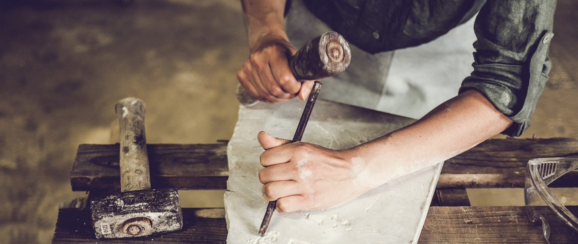 Marbrier qui entretien une pierre tombale.