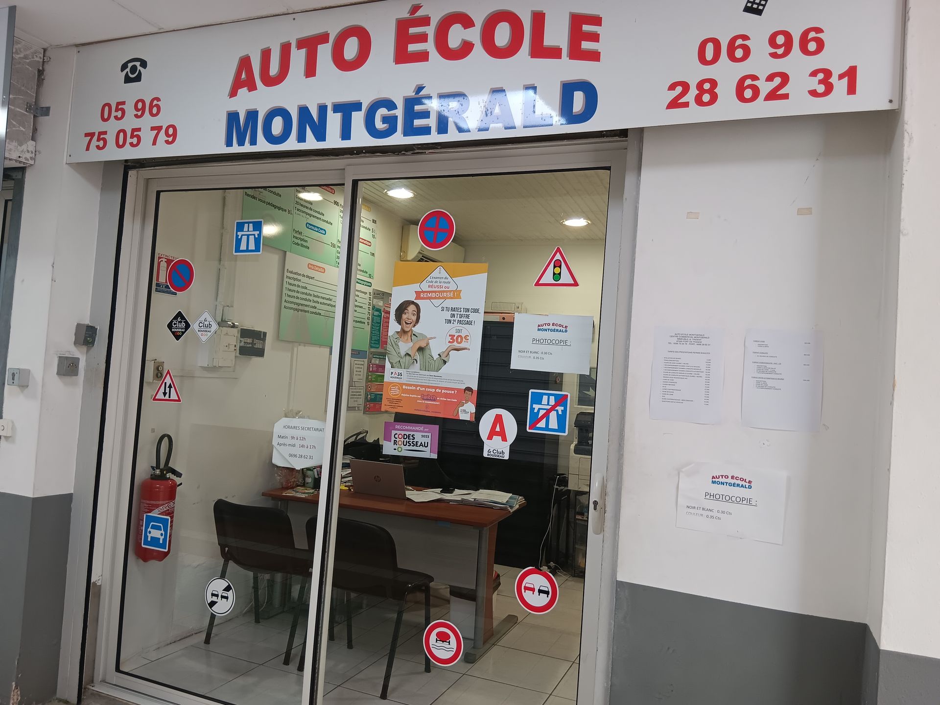 Façade de l'Auto-École Montgérald. Entrée avec panneaux de signalisation et numéros de téléphone.