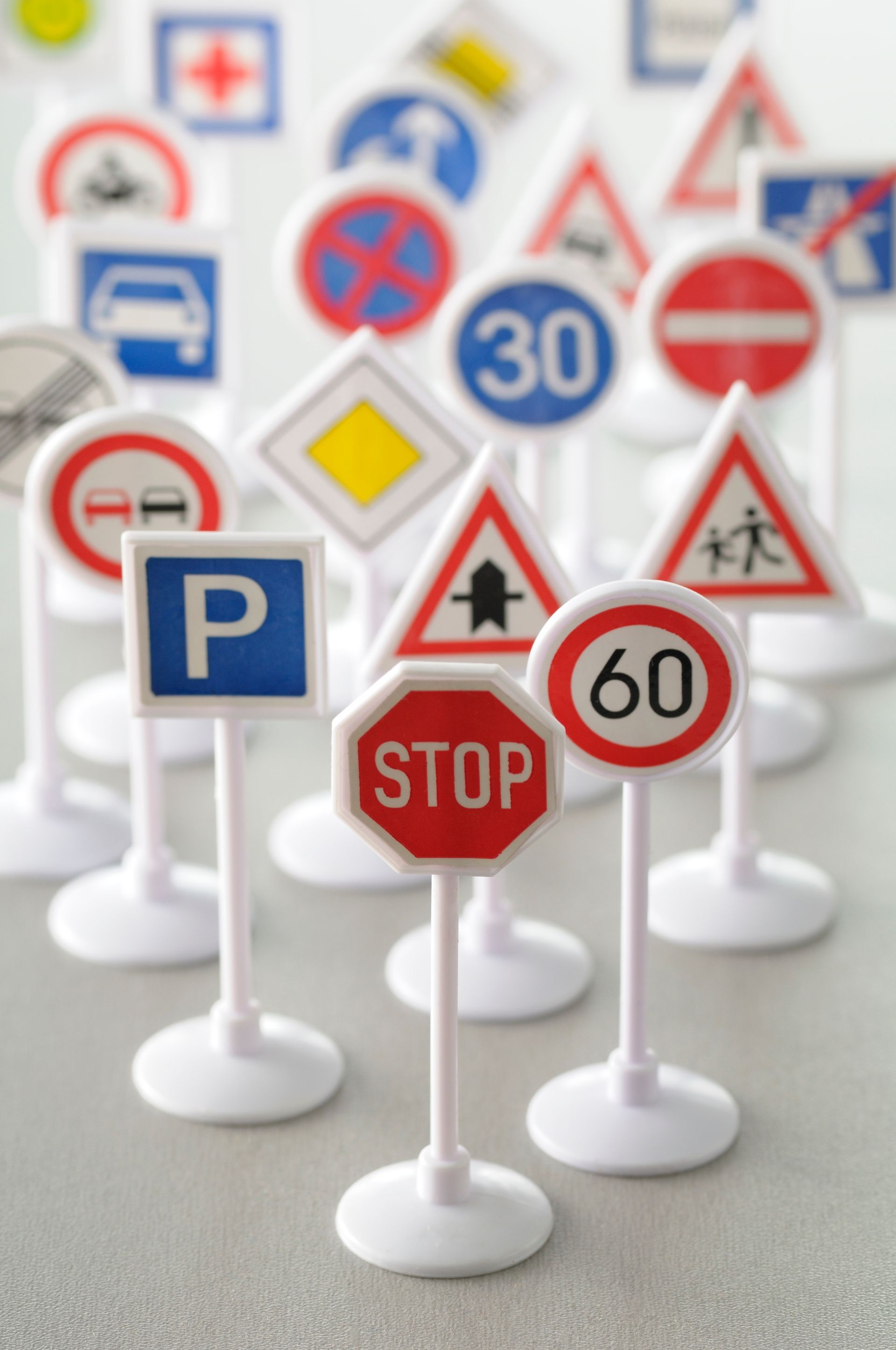 Panneaux de signalisation miniatures de formes et de couleurs variées sur une surface claire.