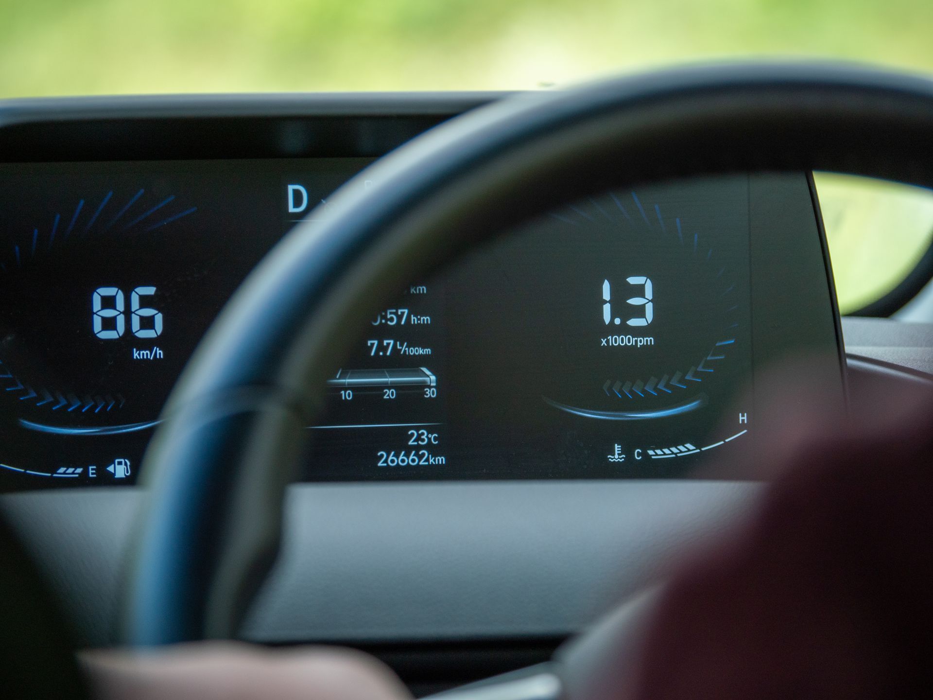 Tableau de bord d'une voiture affichant la vitesse 86 km/h et la consommation d'énergie (1,3 kWh/100 km) derrière un volant.