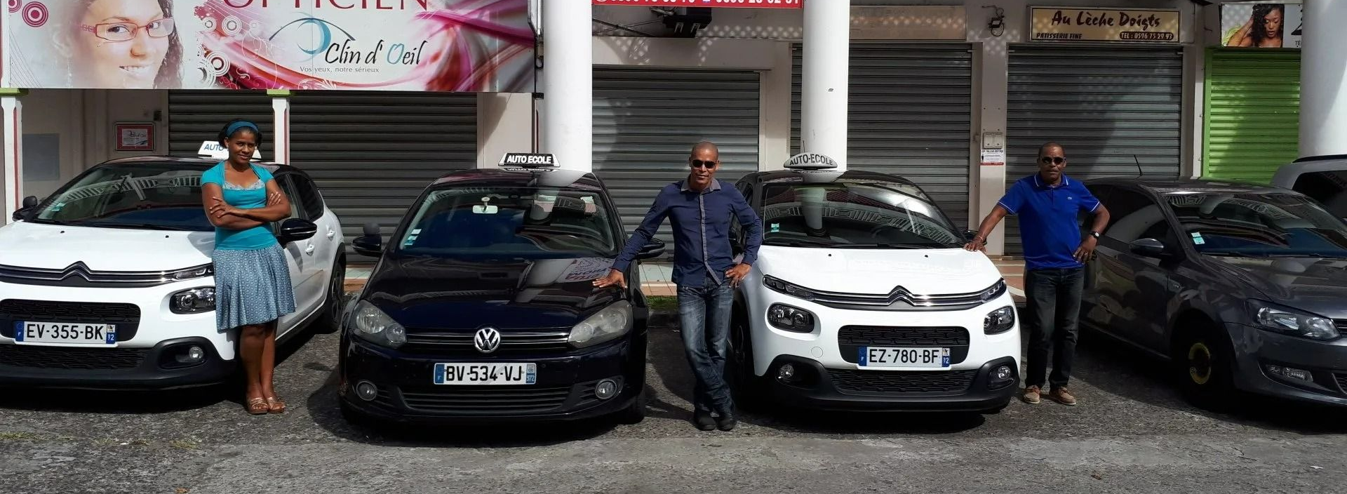 Des personnes posent avec quatre voitures devant un magasin.