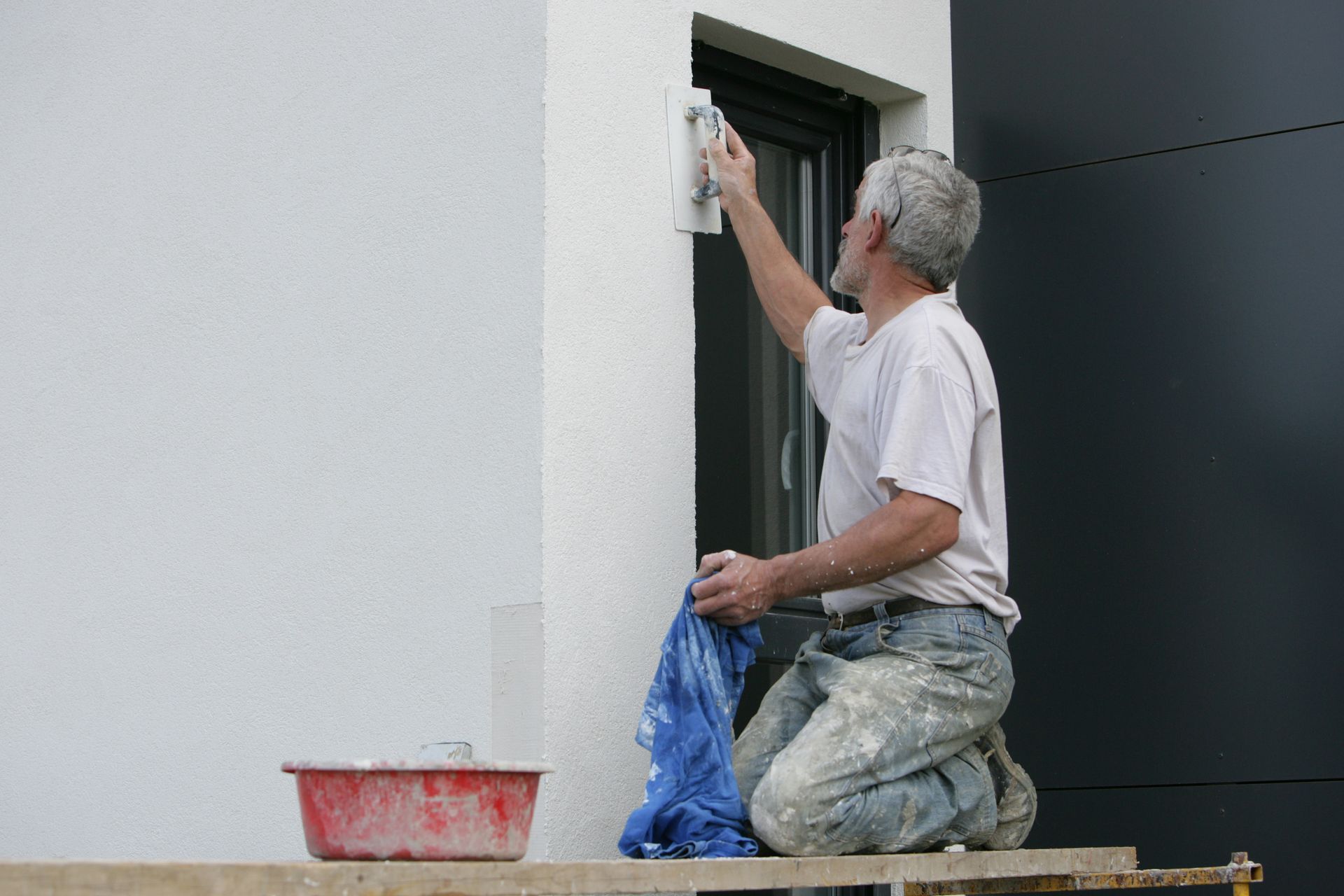 Artisan travaillant le crépi d'un mur extérieur 