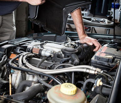 Un homme travaille sur un moteur de voiture avec le capot ouvert