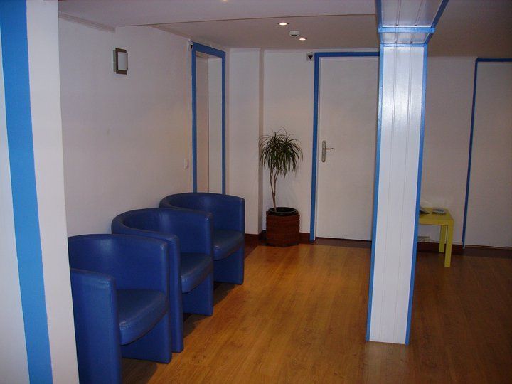 Uma sala de espera com cadeiras azuis e uma planta em vaso