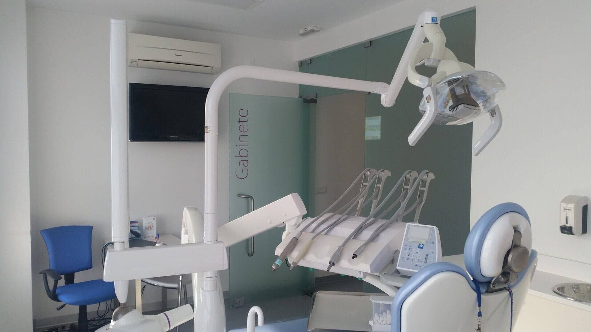 Um consultório odontológico com uma cadeira azul e uma cadeira odontológica