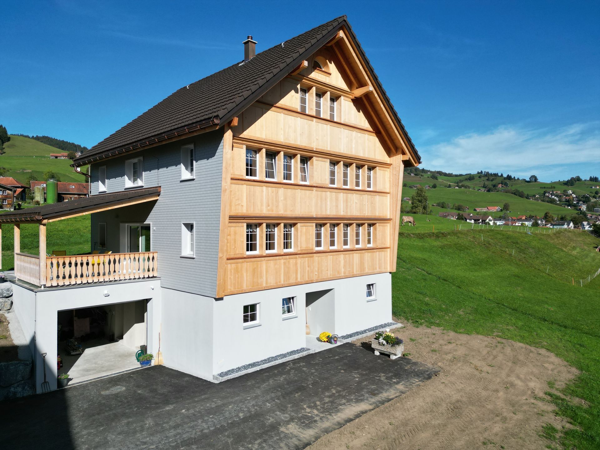 Ein großes weißes Haus mit Holzdach steht inmitten einer Wiese.