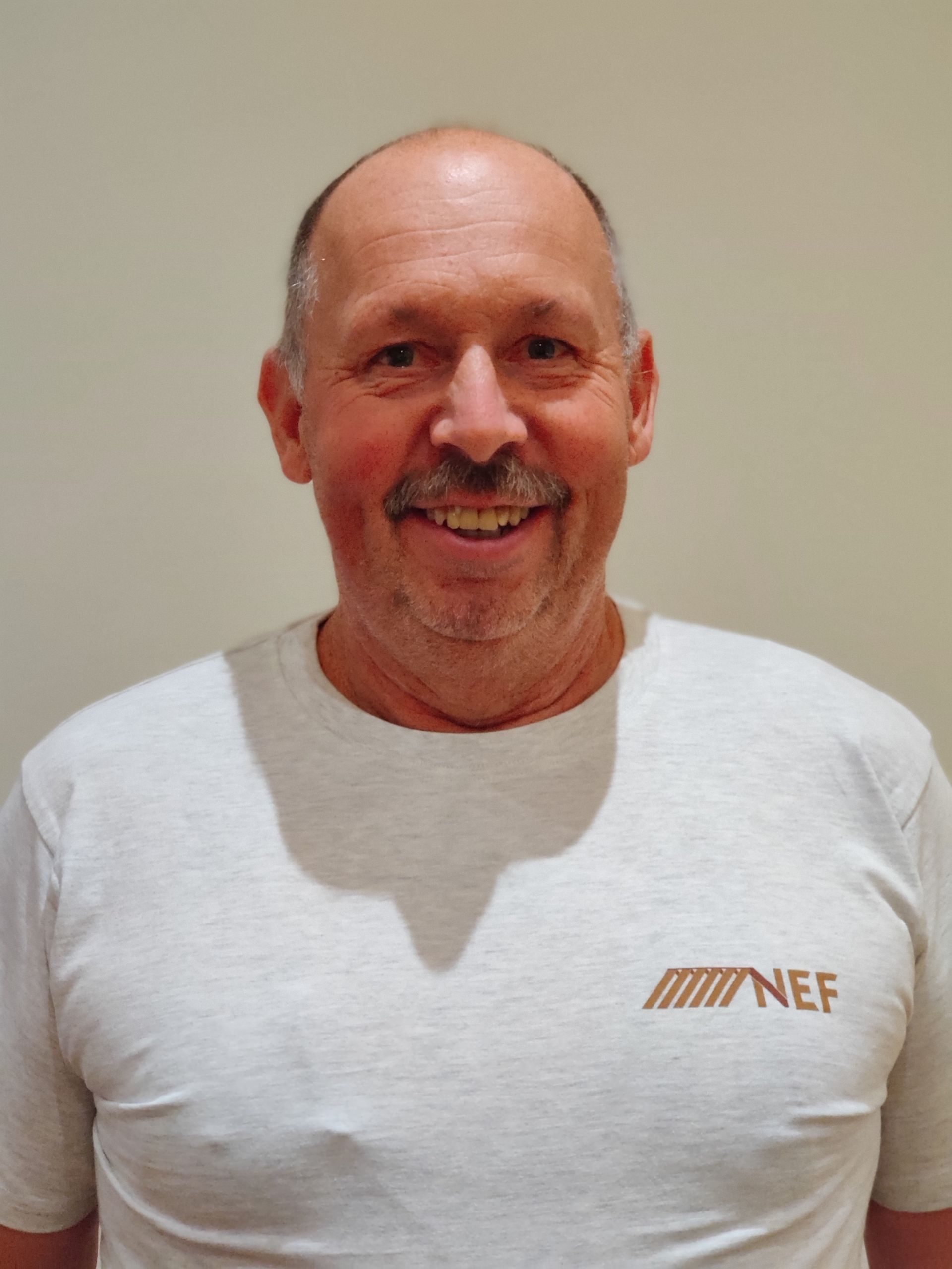 Ein Schreiner in einem Nef T-Shirt lächelt in die Kamera