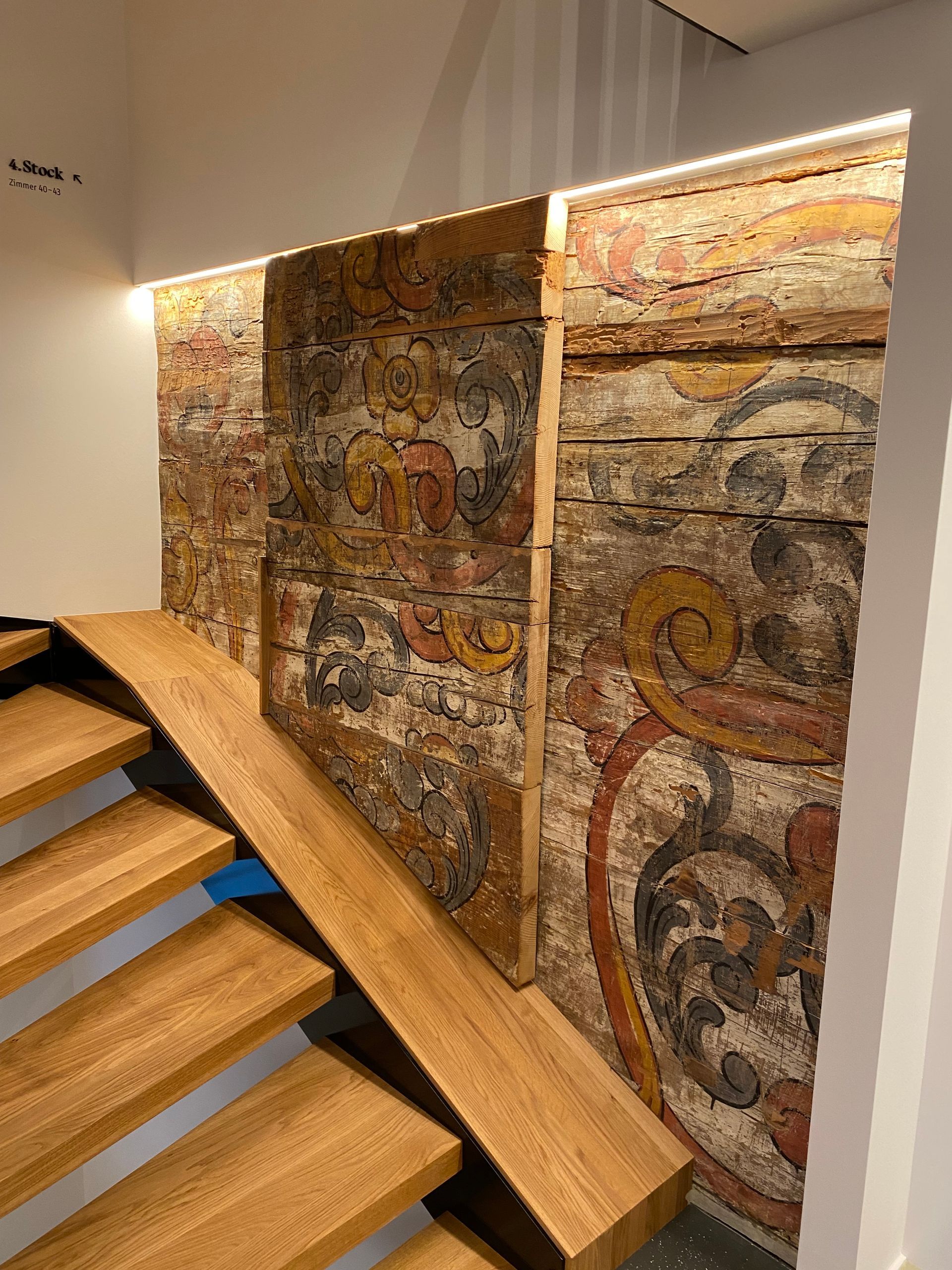 Eine Holztreppe mit einem Gemälde an der Wand dahinter.