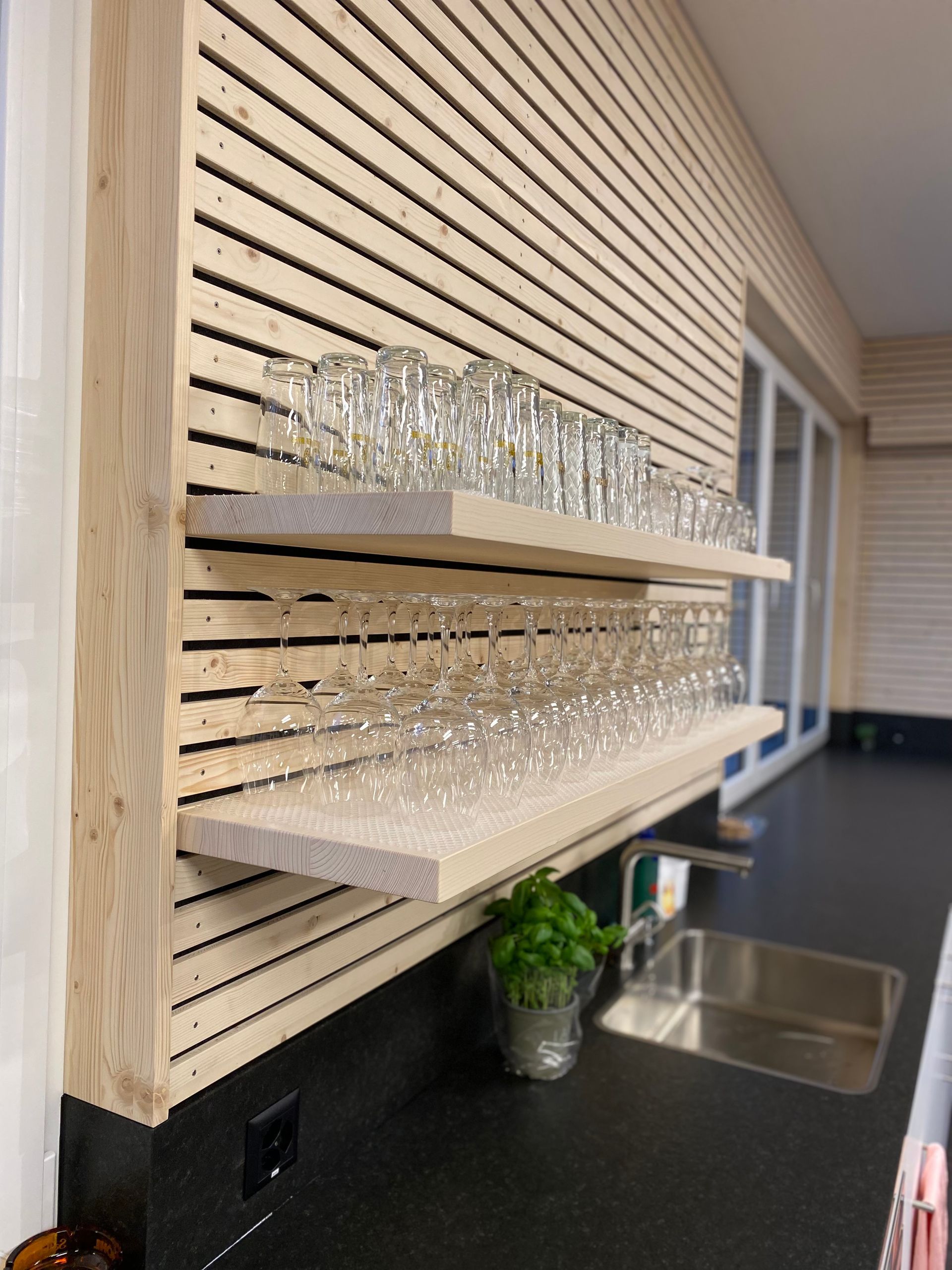Eine Küche mit einem Regal voller Weingläser und einer Spüle