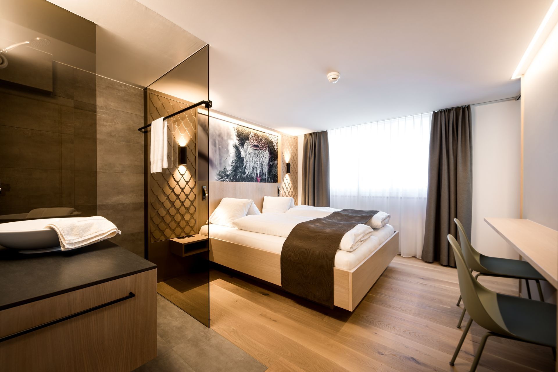 Ein Hotelzimmer mit Bett, Schreibtisch, Stühlen und ebenerdiger Dusche.