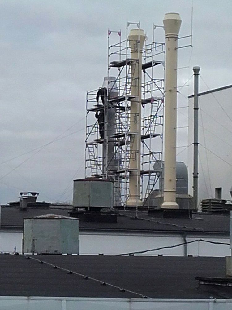 Schornstein mit Gerüst auf einem Industriegebäude. Foto von der VRBA Gerüstbau & Containerservice GmbH.