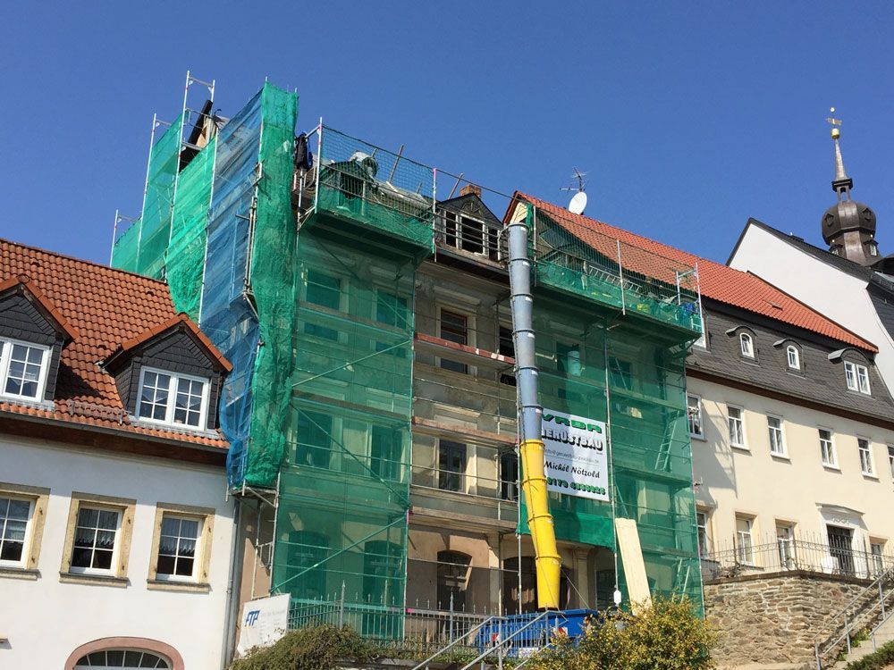 Ein Gebäude mit einem Gerüst an der Seite wird umgebaut. Foto von der VRBA Gerüstbau & Containerservice GmbH.